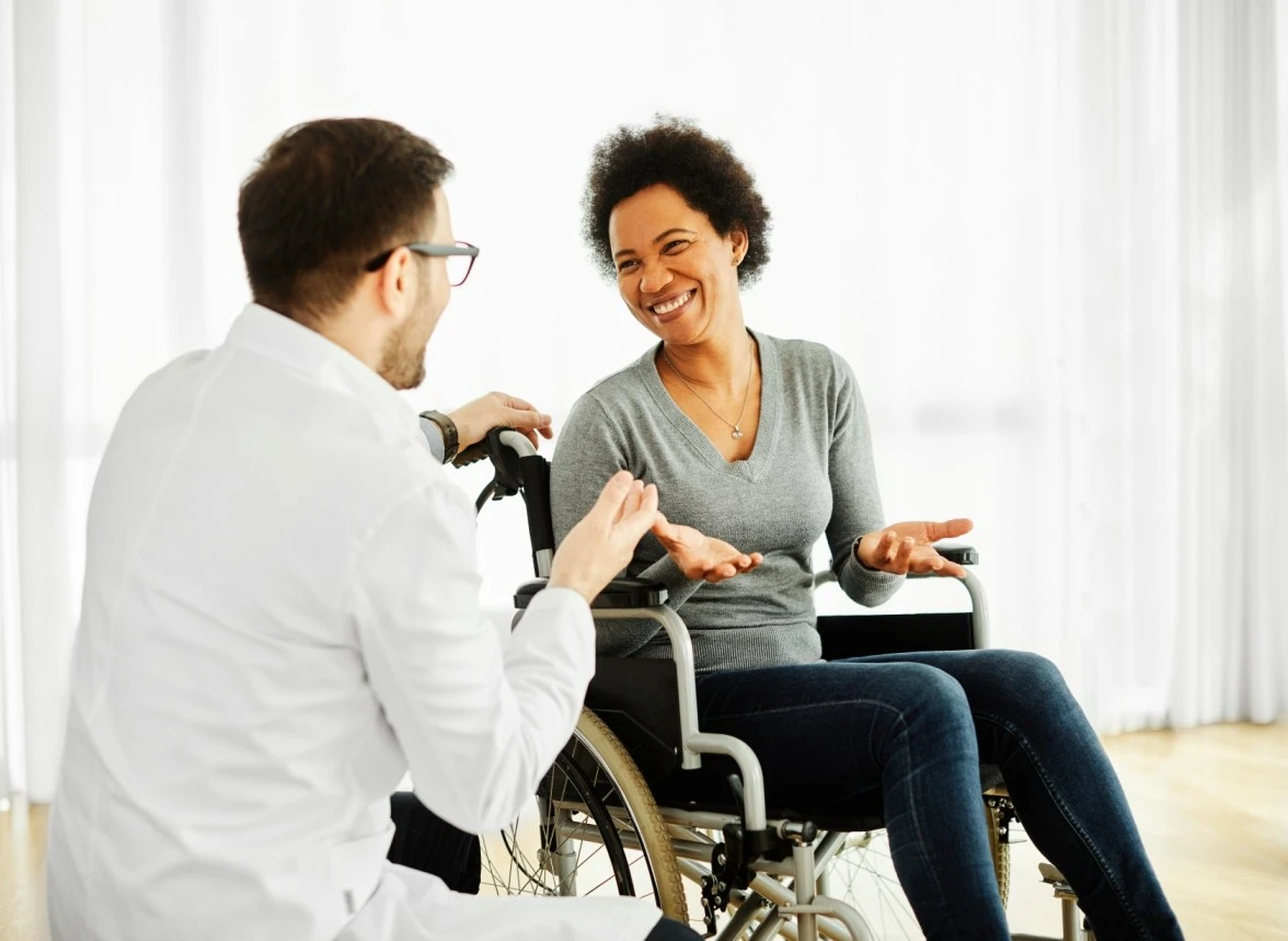 Woman in wheelchair smiling with nurse in home