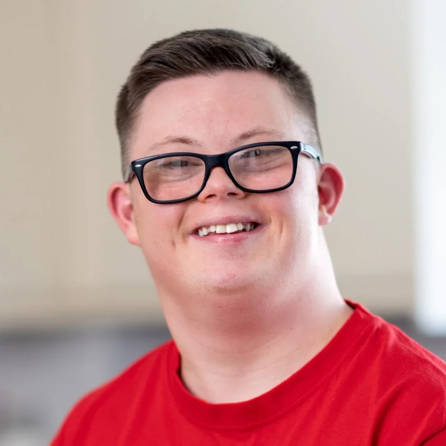 Disabled boy with glasses smiling at camera