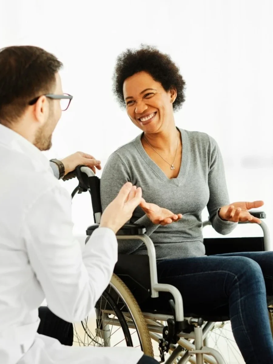 Woman in wheelchair smiling with nurse in home